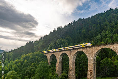 Historic railway bridge with a yellow train at the Ravenna Gorge Black Forest photo