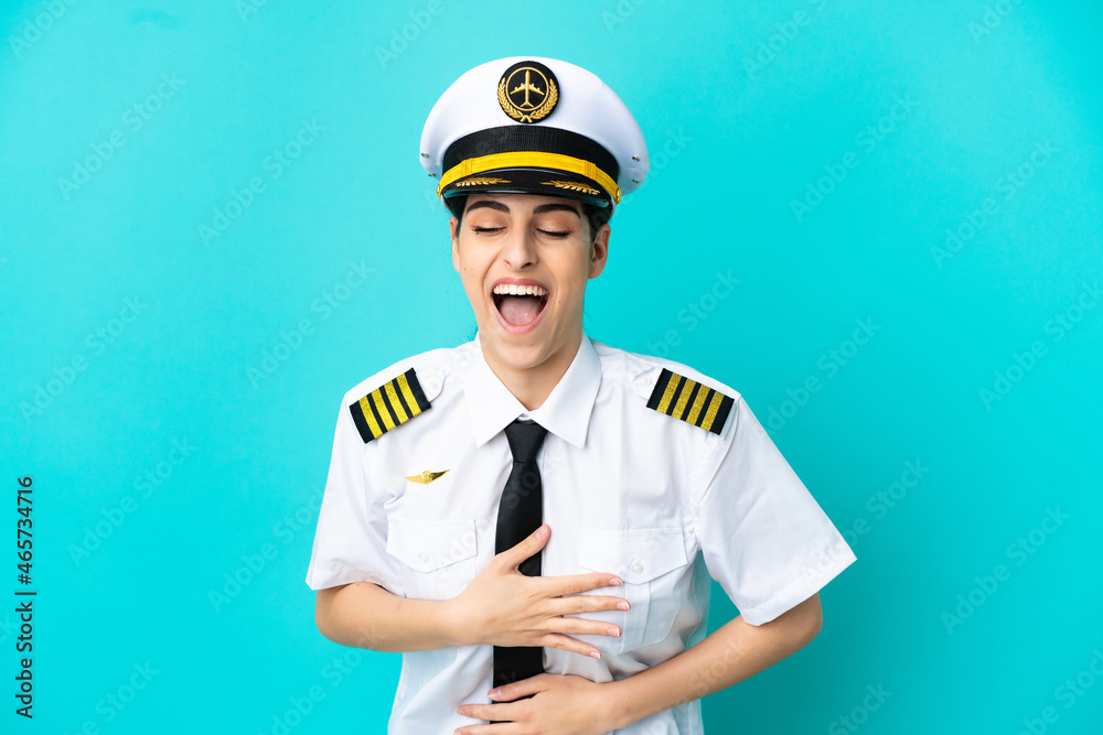 Airplane pilot caucasian woman isolated on blue background smiling a lot Airplane pilot caucasian woman isolated on blue background smiling a lot