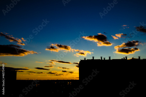 Sunset on the background of the city, beautiful sunlit clouds and black silhouettes of houses