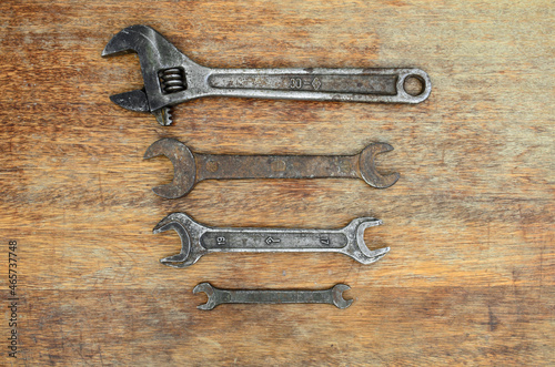 Old tools rusty wrenches of different sizes lie in a row on an old wooden background