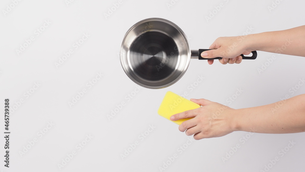 Pot cleaning. Man hand on white background cleaning the non stick pot with handy dish washing sponge which yellow color on the soft side and green on hard side for hygiene after cook. Electric pot. Pot cleaning. Man hand on white background cleaning the non stick pot with handy dish washing sponge which yellow color on the soft side and green on hard side for hygiene after cook. Electric pot.