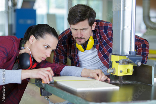 female carpenter working with wood under control of coworker photo