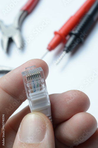 internet cable with a connector rj 45 in the hand of the master. against the background of tools.
