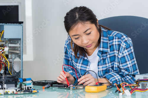 asian woman testing computer component with multimeter