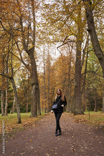 girl in dark clothes among tall autumn trees © Elena