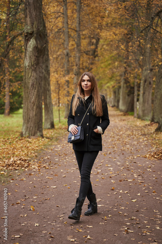 girl in dark clothes with long hair on the track in the autumn park