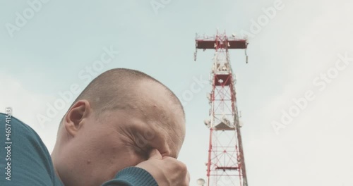 4G and 5G cellular radio tower, the man has a bad headache. The concept of harmful effects of powerful radio waves, high frequency on human health