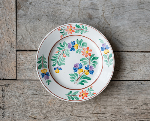 Vintage porcelain plate with folk art flower pattern - on a rustic wooden table