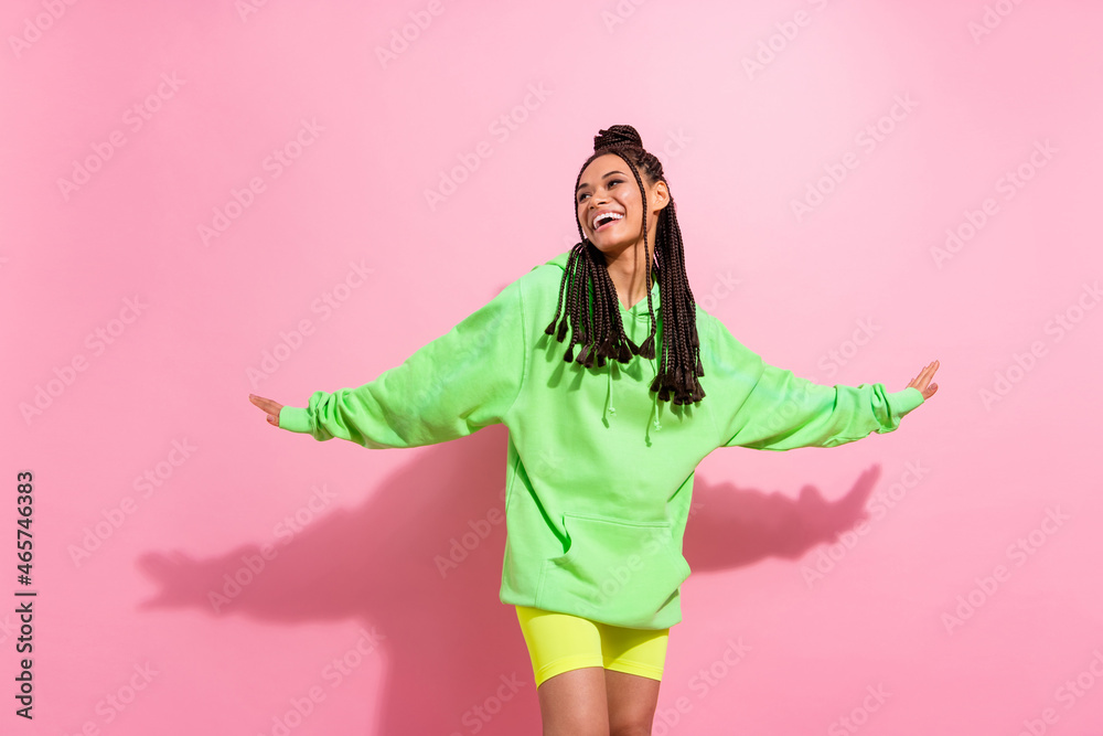 Photo of attractive young dark skin woman look empty space dance good mood isolated on pink color background