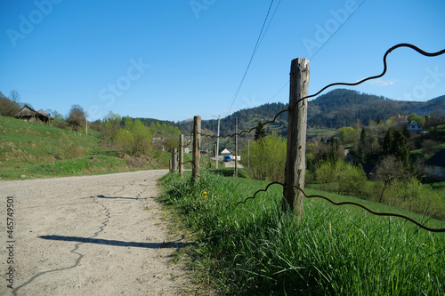 Old fence near the dirt road in the mountain village in Carpathians, Ukraine