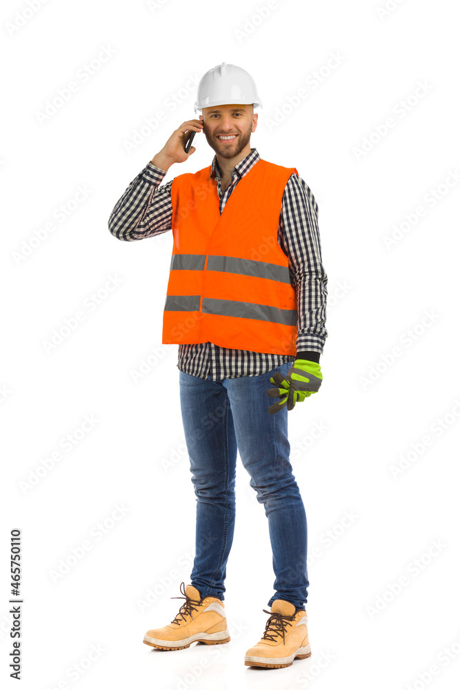 Foreman in white helmet and reflective waistcoat is talking on the phone. Full length isolated. Foreman in white helmet and reflective waistcoat is talking on the phone. Full length isolated.