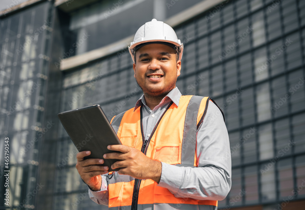 Young worker indian civil engineer using tablet planning the project build the modern construction reading the blueprint. Asian Architecture or engineer working in the building construction site. Young worker indian civil engineer using tablet planning the project build the modern construction reading the blueprint. Asian Architecture or engineer working in the building construction site.