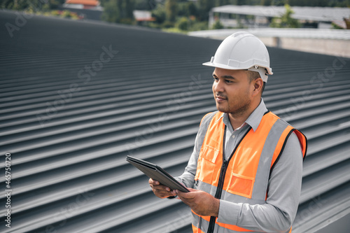 Asian male architect or engineer using tablet control planning construction building. Civil engineers work on the roof of a modern building. Standing on the top floor roof with the sunset
