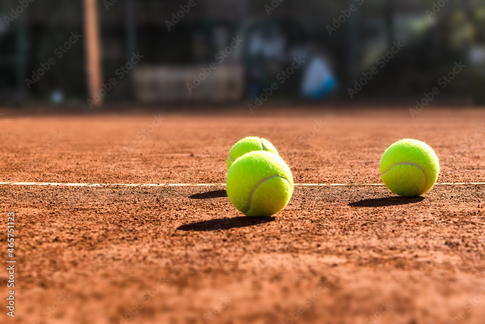 Close up of three tennis balls on a tennis clay court. Red clay court.
