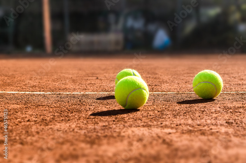 Close up of three tennis balls on a tennis clay court. Red clay court.  © Ivan