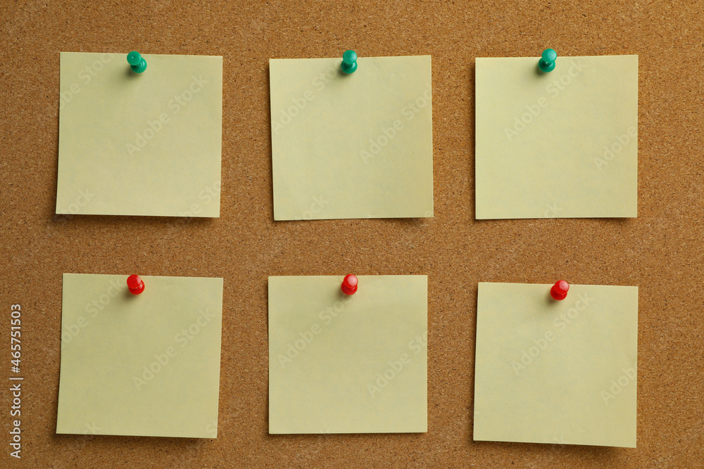 Beige paper notes pinned to cork board Beige paper notes pinned to cork board