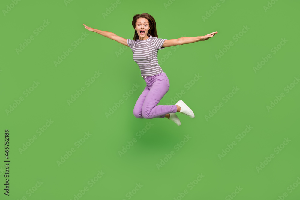 Full length body size view of attractive cheerful girl jumping fooling having fun isolated over vivid green color background Full length body size view of attractive cheerful girl jumping fooling having fun isolated over vivid green color background