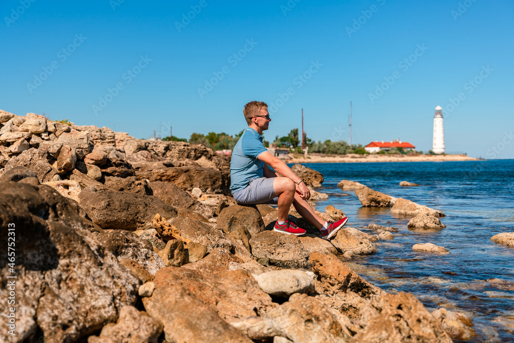 A young man on the Black Sea coast far from the Chersonesos lighthouse. Beautiful summer landscape in Crimea.