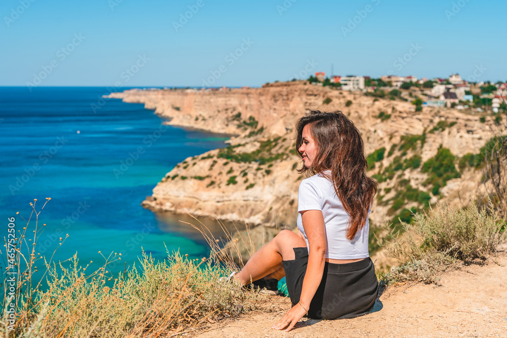 A young beautiful woman travels to Cape Fiolent, the most famous place in Crimea with an azure wave and rocks