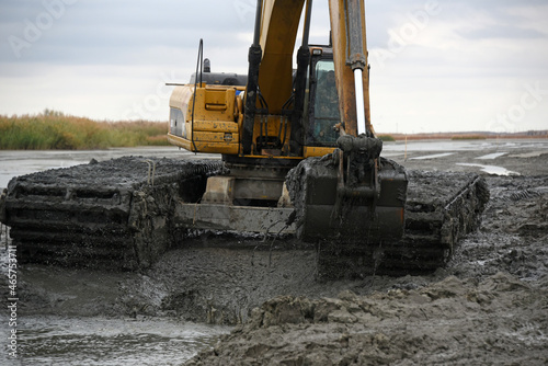 Amphibious water excavator clears the dried river bed channel from the bed silt