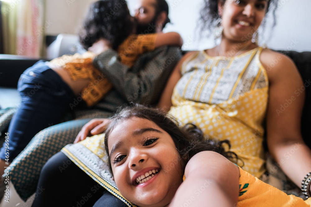 © DisobeyArt - Happy girl child taking selfie with mobile phone camera at home with family in background - Focus on kid face © DisobeyArt - Happy girl child taking selfie with mobile phone camera at home with family in background - Focus on kid face