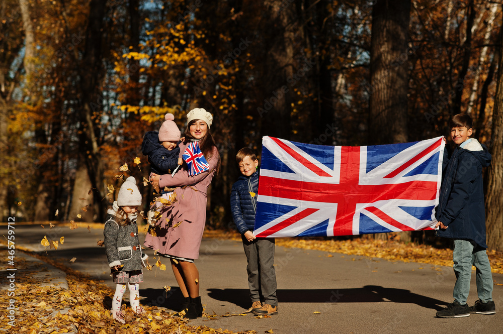 National holiday of United Kingdom. Family with british flags in autumn park.  Britishness celebrating UK. Mother with four kids.