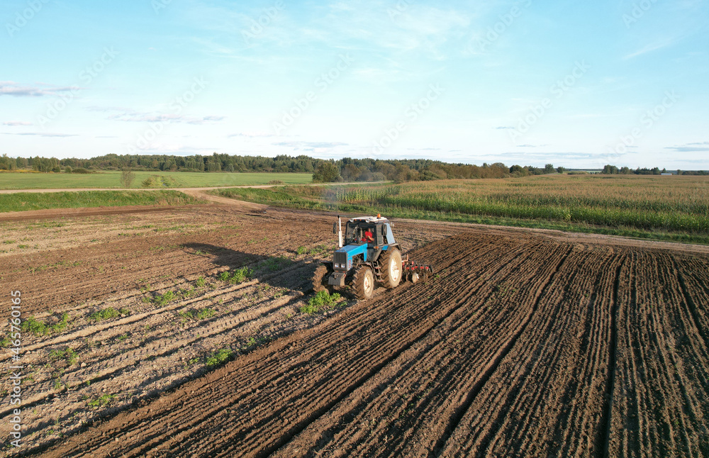 Tractor with Plough on Plowed. Ploughing and Soil Tillage. Agricultural Tractor on Cultivation Field for Sowing Seeds. Tractor During Field Cultivating. Planting and Seeding Equipment.