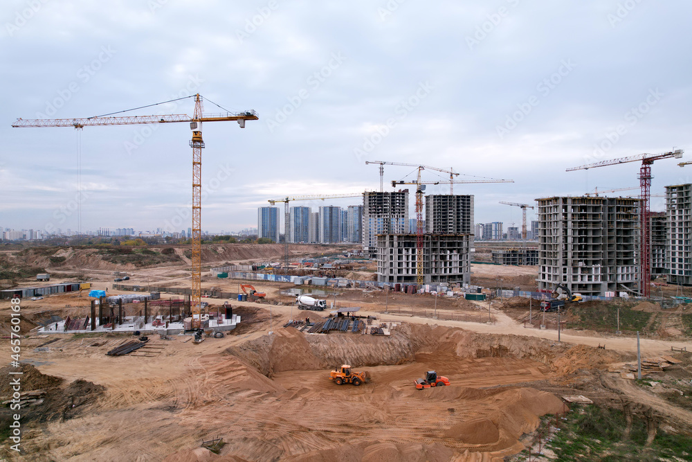 Tower crane at buildings construction. Soil Compactor at construction site. Vibration single-cylinder road roller leveling the ground for the construct of the foundation for residential building.