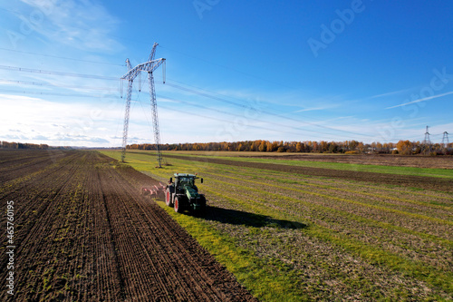 Tractor with Plough on Plowed. Ploughing and Soil Tillage. Agricultural Tractor on Cultivation Field for Sowing Seeds. Tractor During Field Cultivating. Planting and Seeding Equipment.