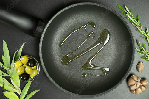 Canvas Print Top view of frying pan with olive oil and ingredients around it on dark background