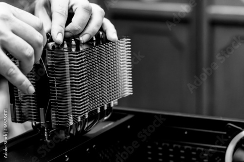 Computer technician installs cooling system of the computer. Hardware developer fixing electronic components. Assembling PC. Selective focus of a computer scientist hands installing a heat sink.