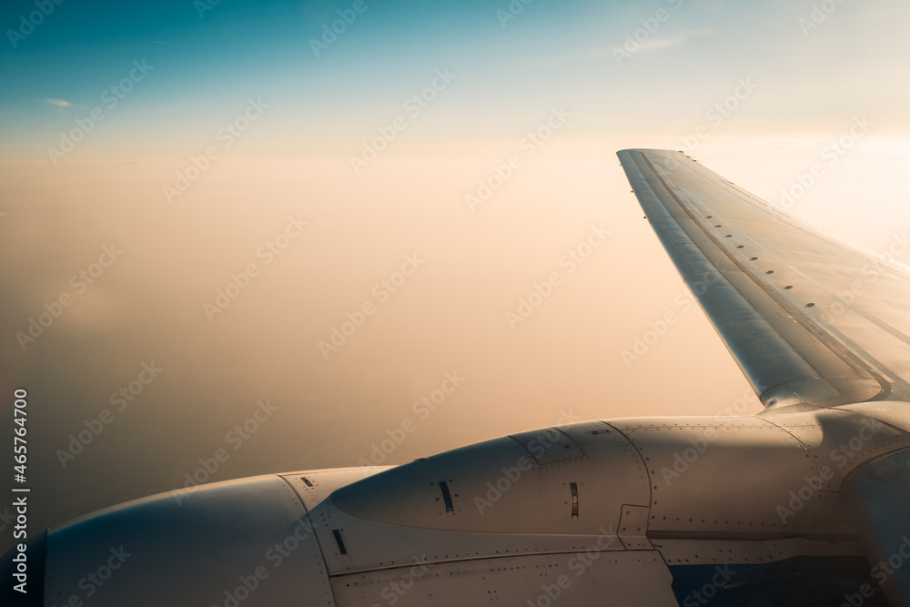 Horizontal shot of airplane wing in flight during sunset.