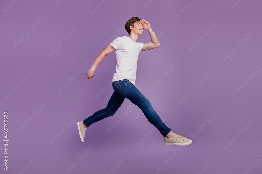 Full body profile side photo of young cheerful man jump walk look ahead forward isolated on violet color background