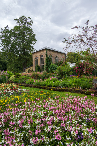Fields of colorful flowers in front of old green house in Lund Botanical Gardens in Sweden