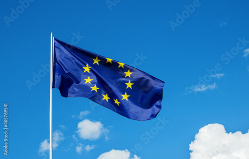 European Union EU flag waving in the wind over cloudy blue sky low angle view close up.