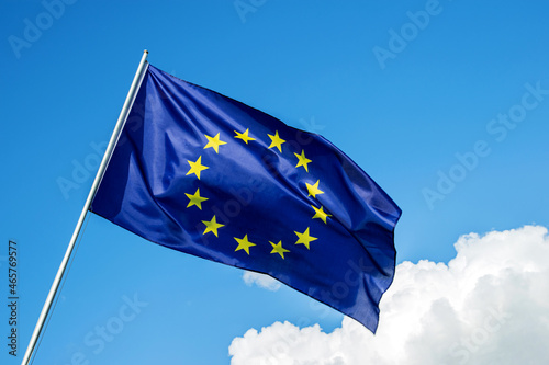 European Union EU flag waving in the wind over cloudy blue sky low angle view close up.