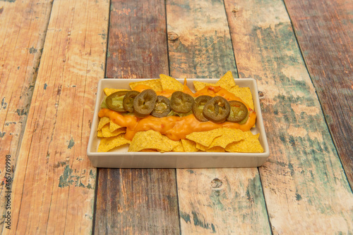 Cheddar nachos with guacamole are a Mexican classic, gratin cheese with fresh hints of guacamole, cilantro, corn chips, and jalapeños.