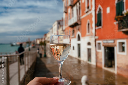 Venice and wine lover with wineglass in a hand. Drinking wine at embankment with old houses of famous italian city