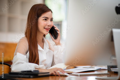Portrait of a beautiful young business Asian female entrepreneur working in modern office, doing finances, accounting analysis, report, data, and pointing graph. © David
