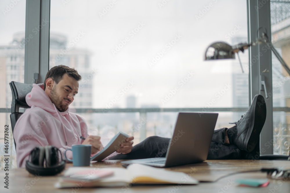 A young, serious man works hard alone in the office at a laptop. A young, serious man works hard alone in the office at a laptop.