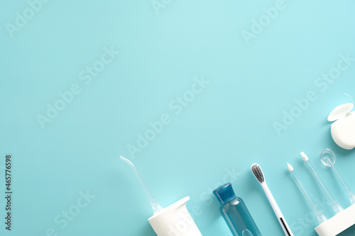 Flat lay Portable Water Pick Flosser, toothbrush, liquid, flosser on blue background. Dental treatment concept.