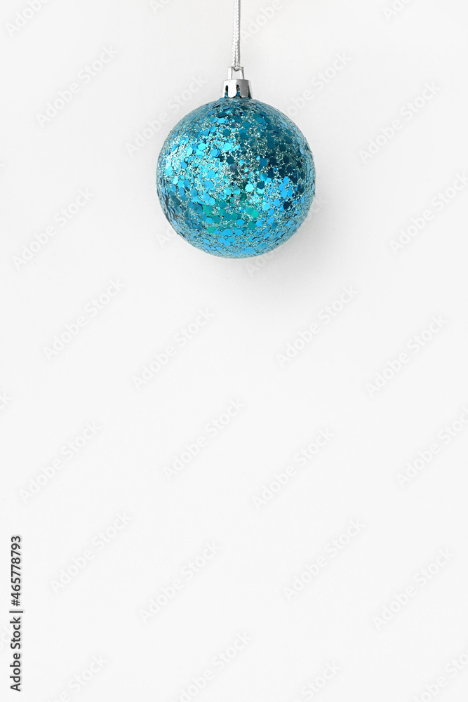 Merry Christmas and Happy New Year. Christmas blue ball hanging on a string on a shimmering shiny white background. Greeting card or banner for website sale.