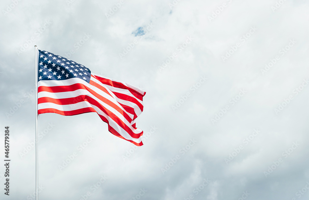 USA America flag waving in the wind over cloudy sky low angle view close up.