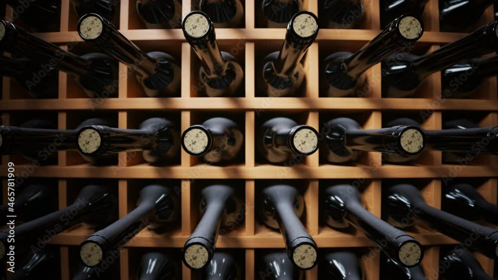 Looping animation of wine bottles ordered on wooden shelves in dark wine-cellar.