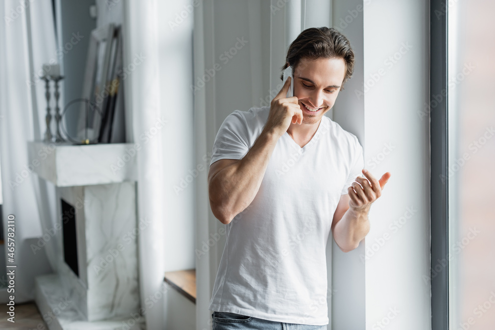 Fototapeta premium cheerful man talking on cellphone at home