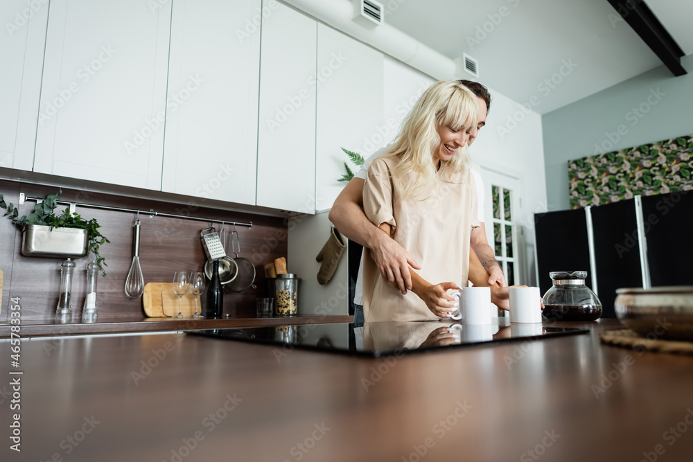 happy couple taking cups of coffee in kitchen