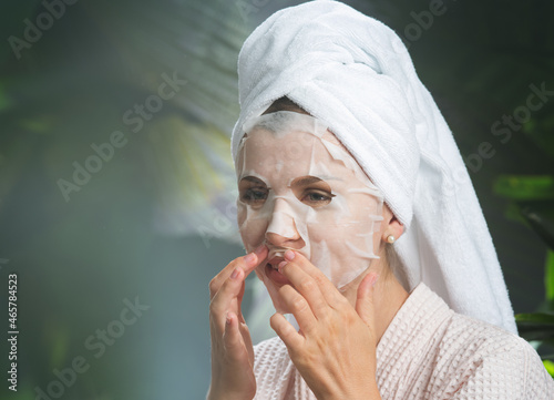 close up portrait of nice young woman applying facial mask photo