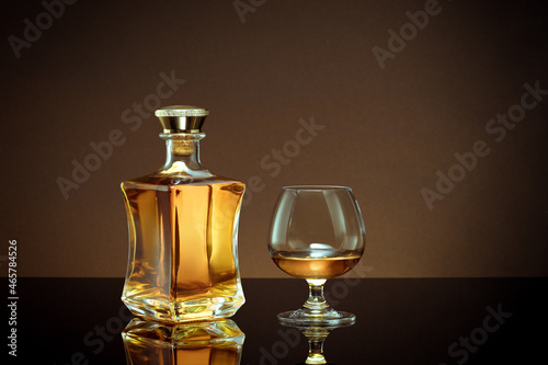 close up view of bottle of whiskey and a glass aside on color back. 