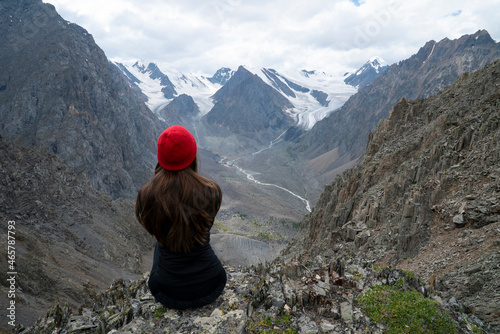 Sports girl in a red hat stands on the top of the mountain
