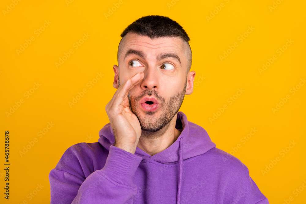 Photo of impressed millennial brunet guy look empty space wear purple hoodie isolated on yellow color background Photo of impressed millennial brunet guy look empty space wear purple hoodie isolated on yellow color background